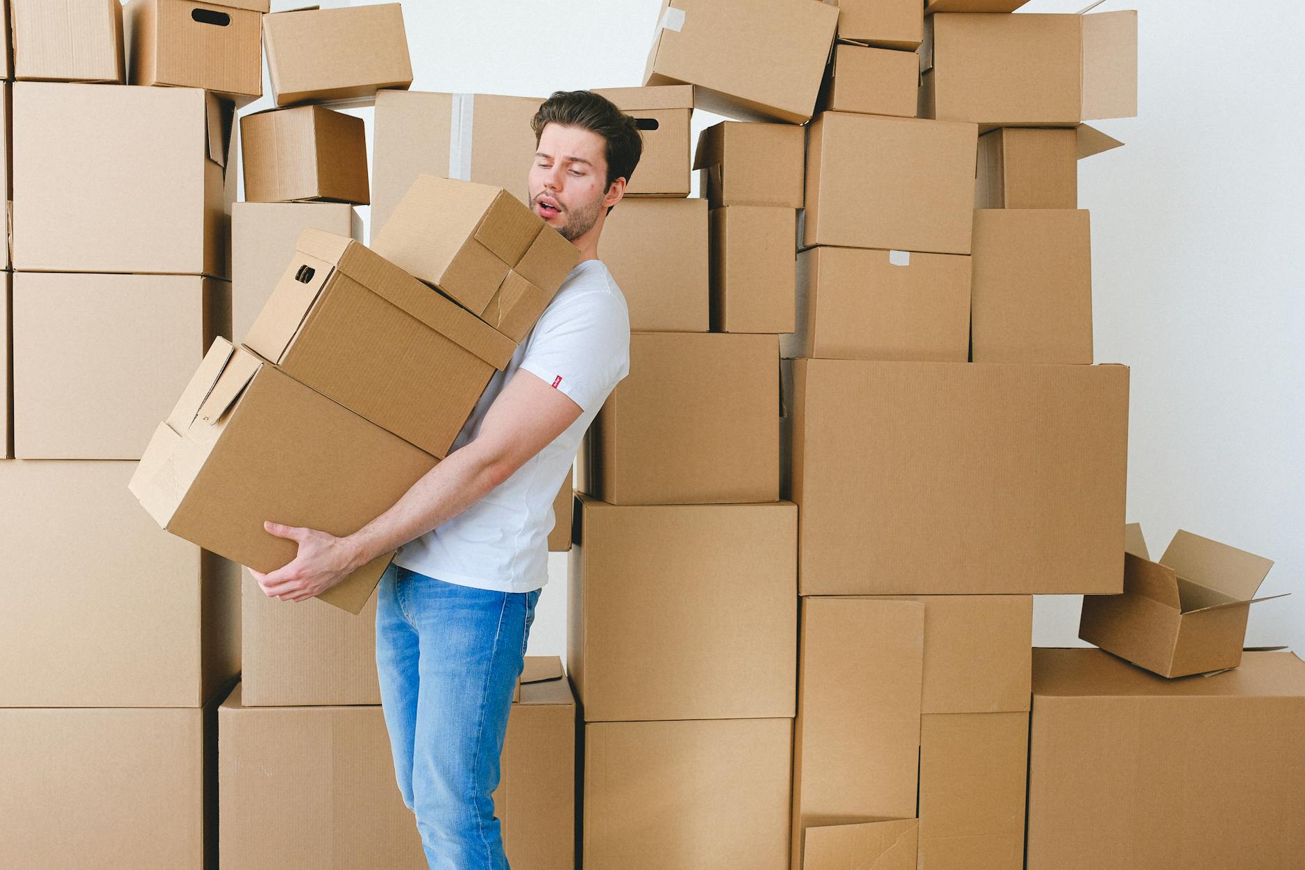 A young person carrying moving boxes into a new apartment