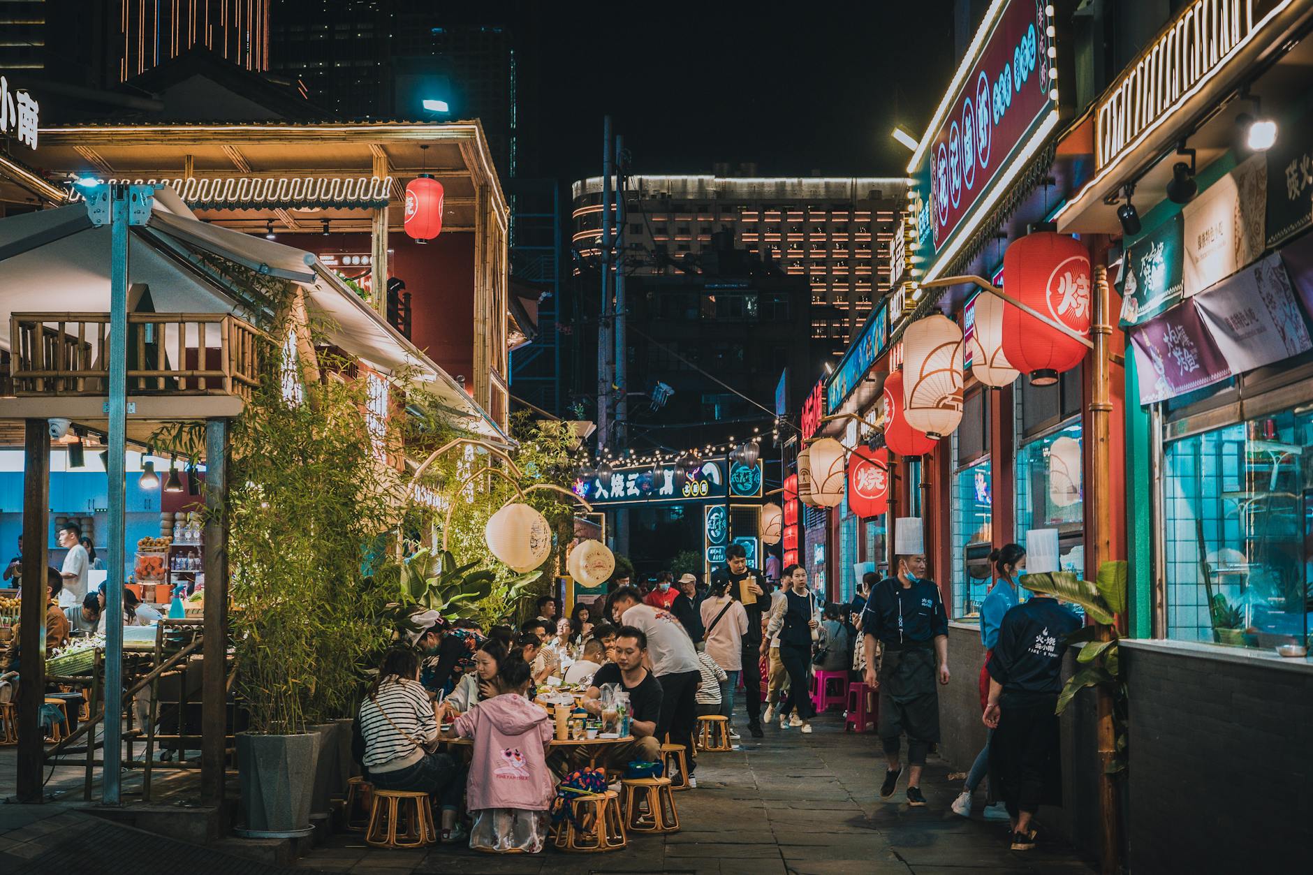A lively street of restaurants and food stalls glowing at night