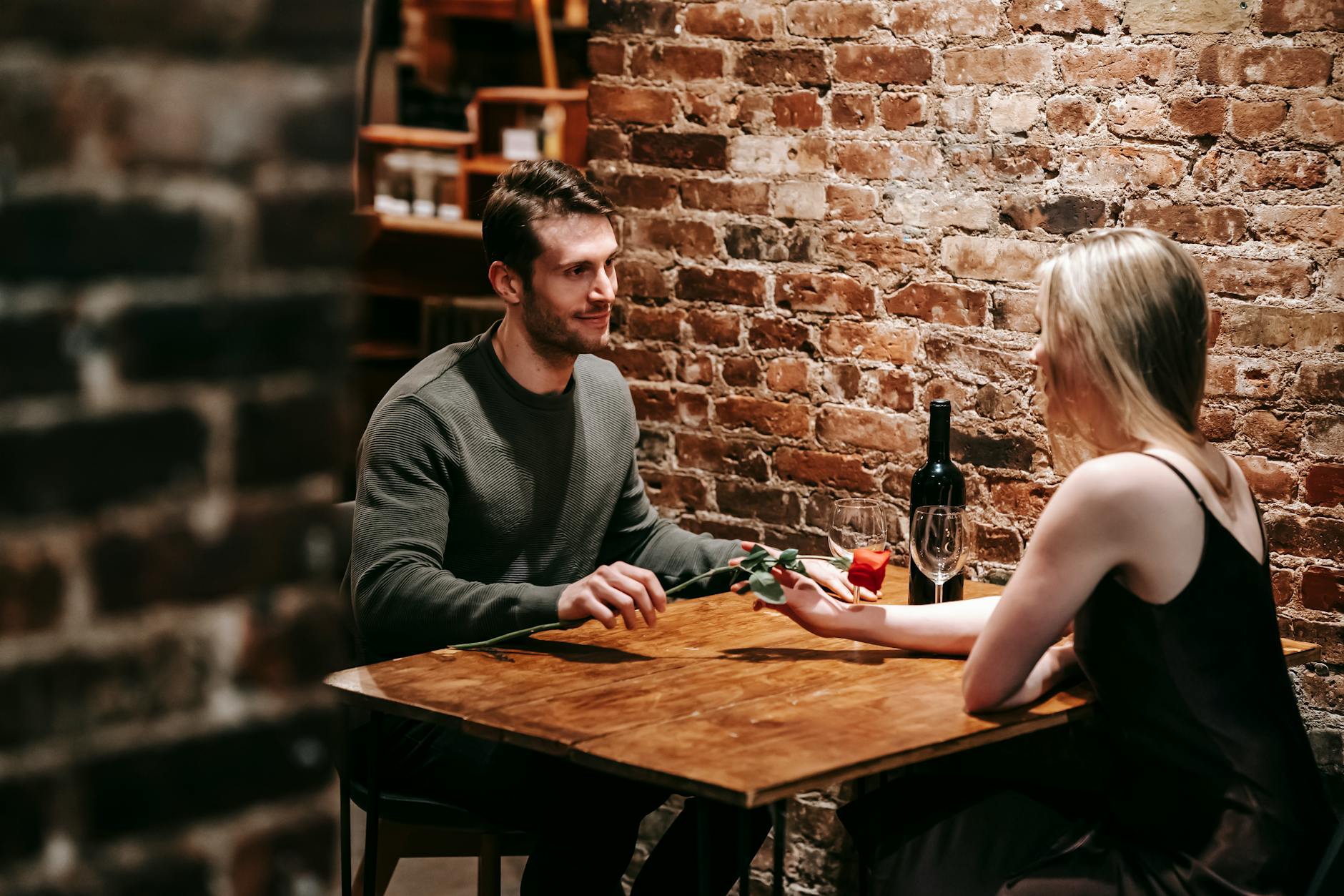 A couple celebrating with a red rose at a candlelit restaurant table