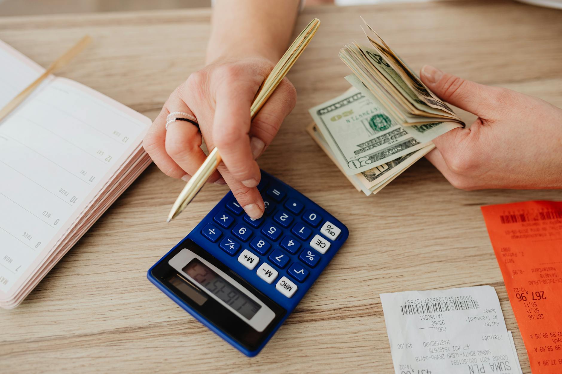 Hands using a calculator and cash for budget planning
