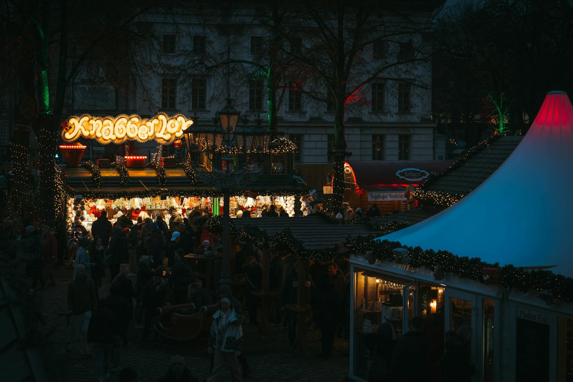 A festive Christmas market at night illuminated by holiday lights