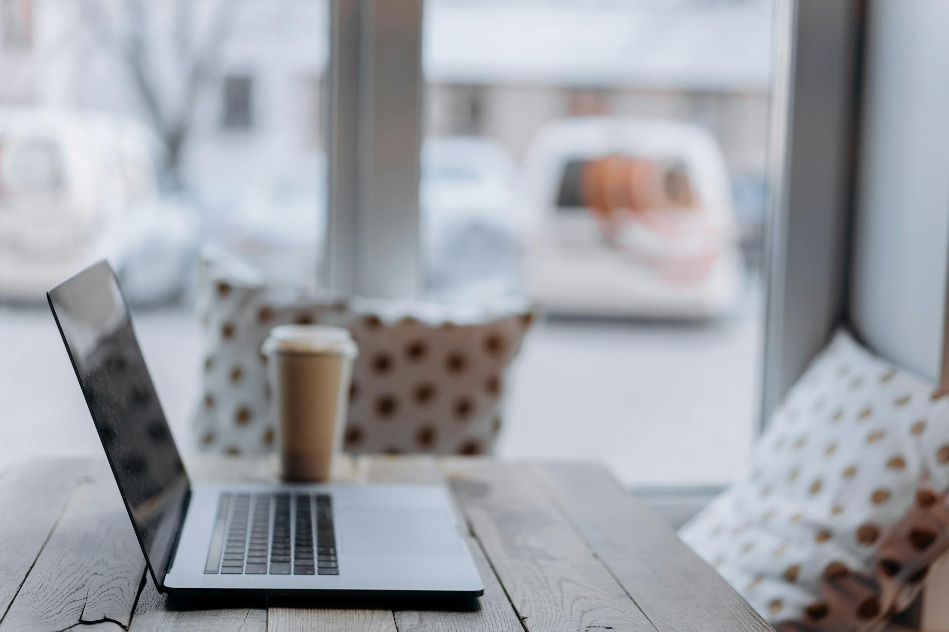A cozy workspace with a laptop and coffee cup by a window