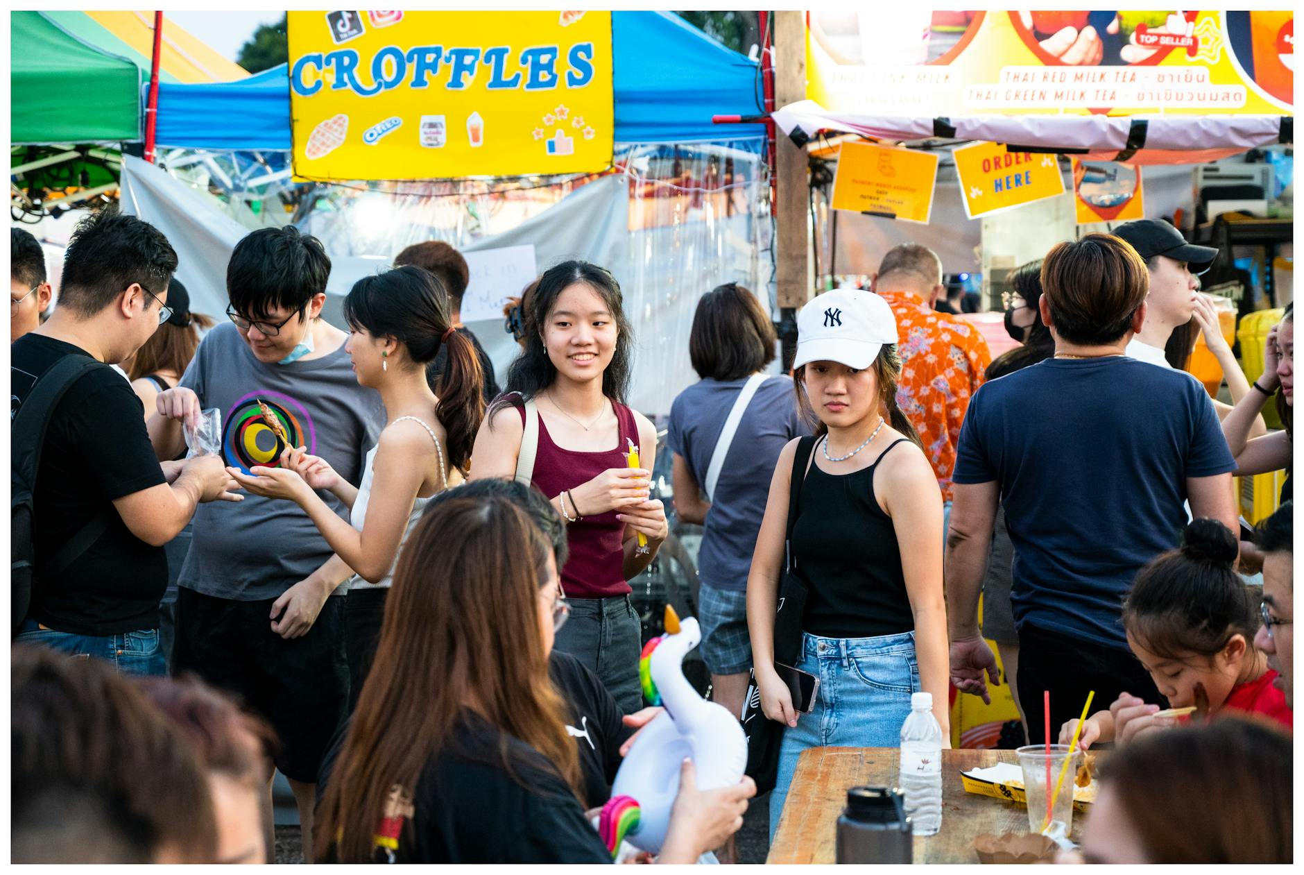 A colorful street festival with people shopping and enjoying food