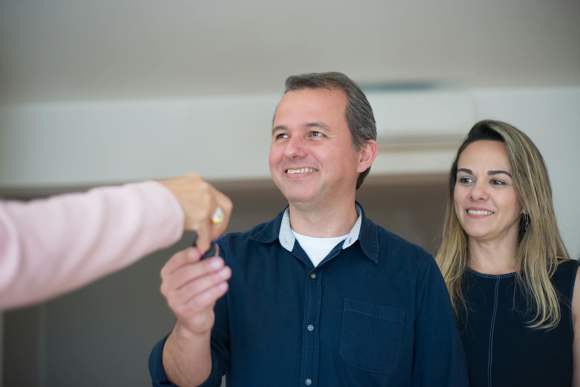 A smiling couple celebrating with keys to a new apartment
