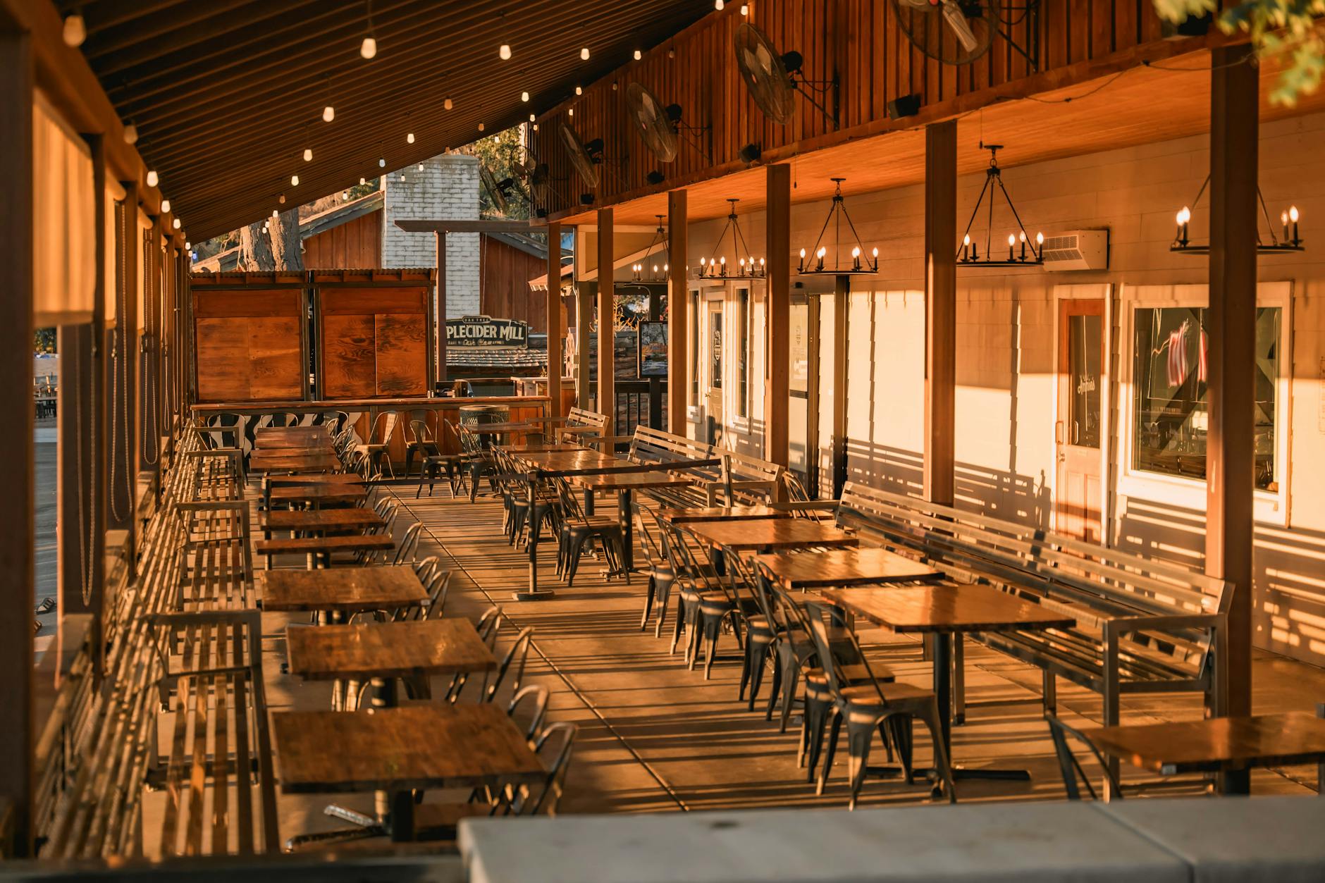 A warm, inviting outdoor patio with wooden tables and string lighting
