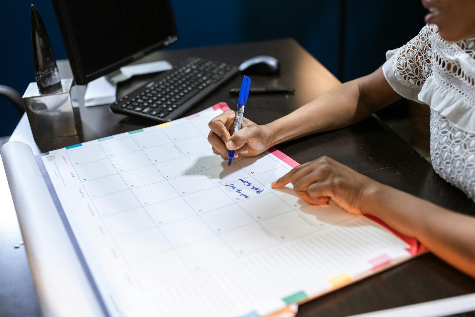 A person writing notes in a desk calendar