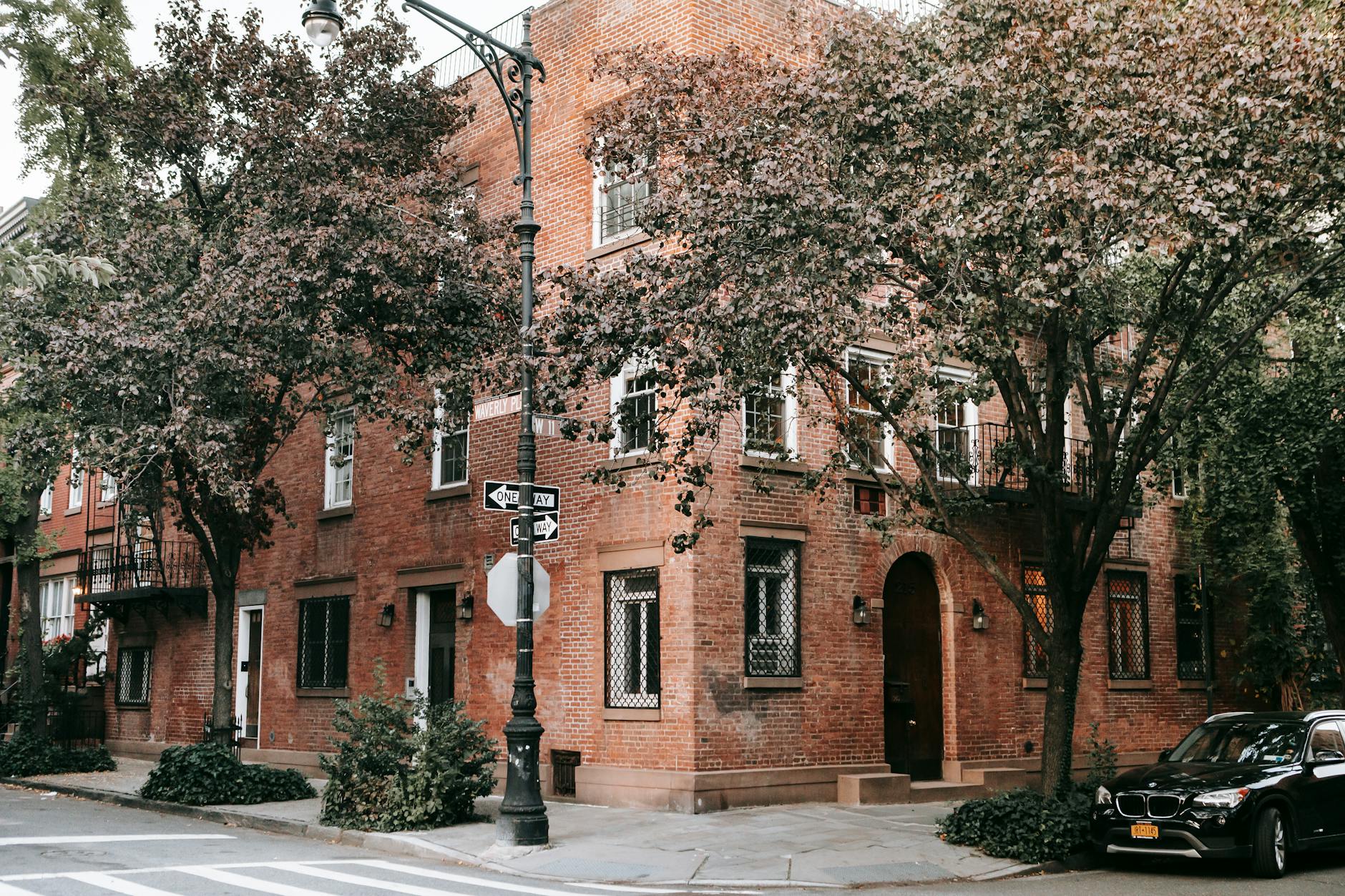 A brick house on a tree-lined city street corner