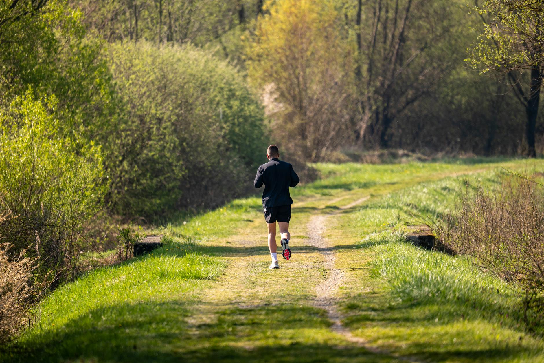 A person jogging on a green path in the morning