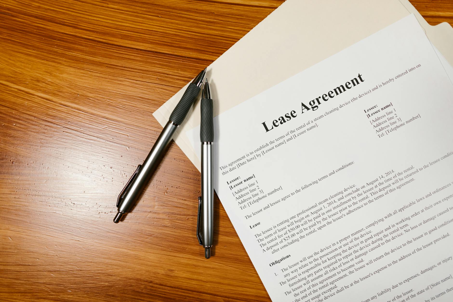 A lease agreement and pens on a wooden desk