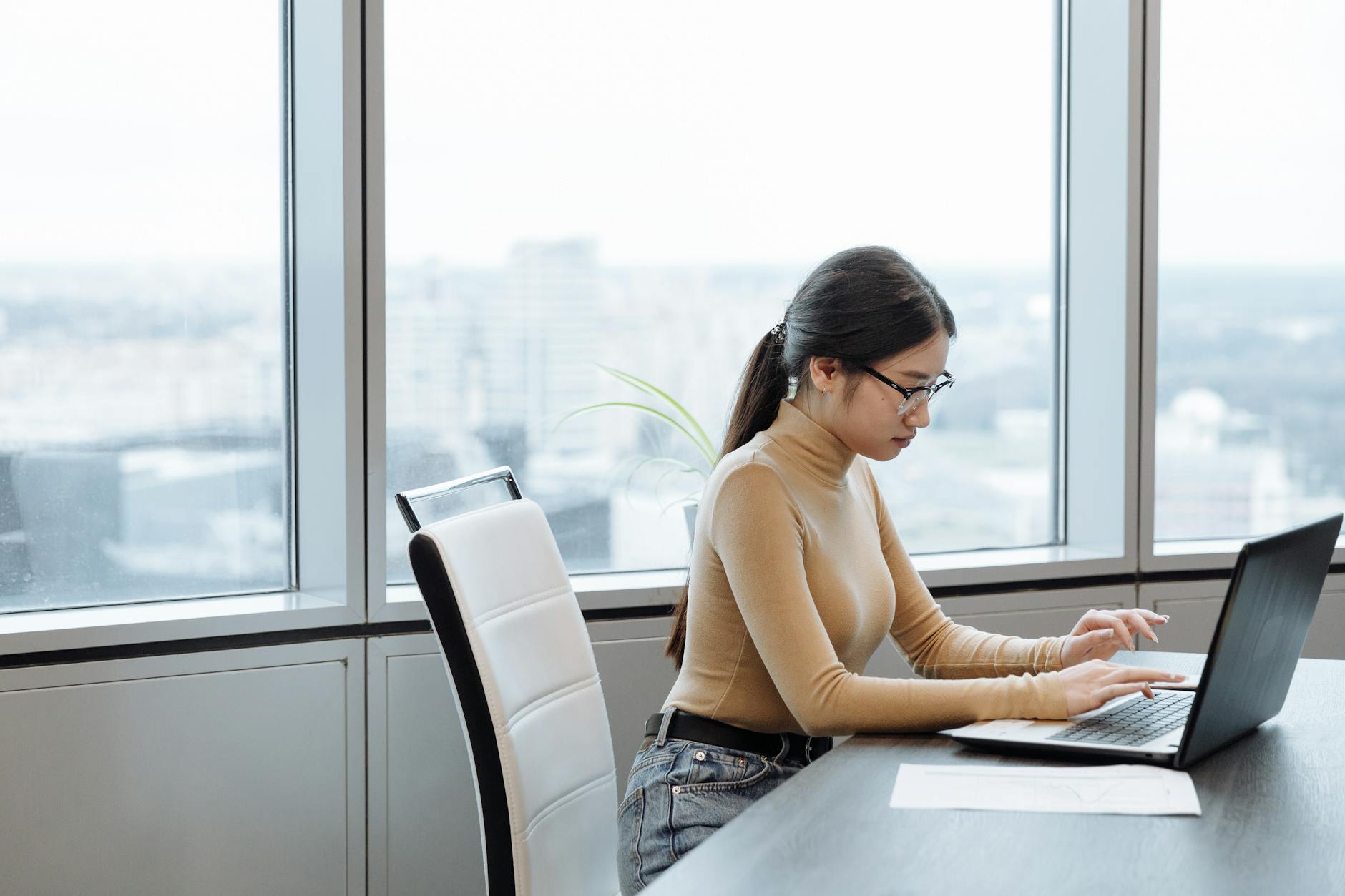 A focused woman typing on a laptop in a bright, modern setting