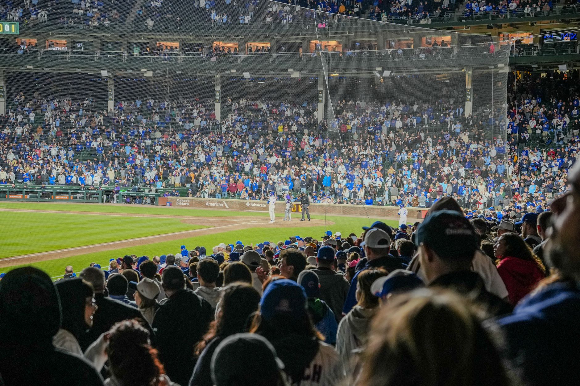 An energetic nighttime baseball game with a packed stadium crowd