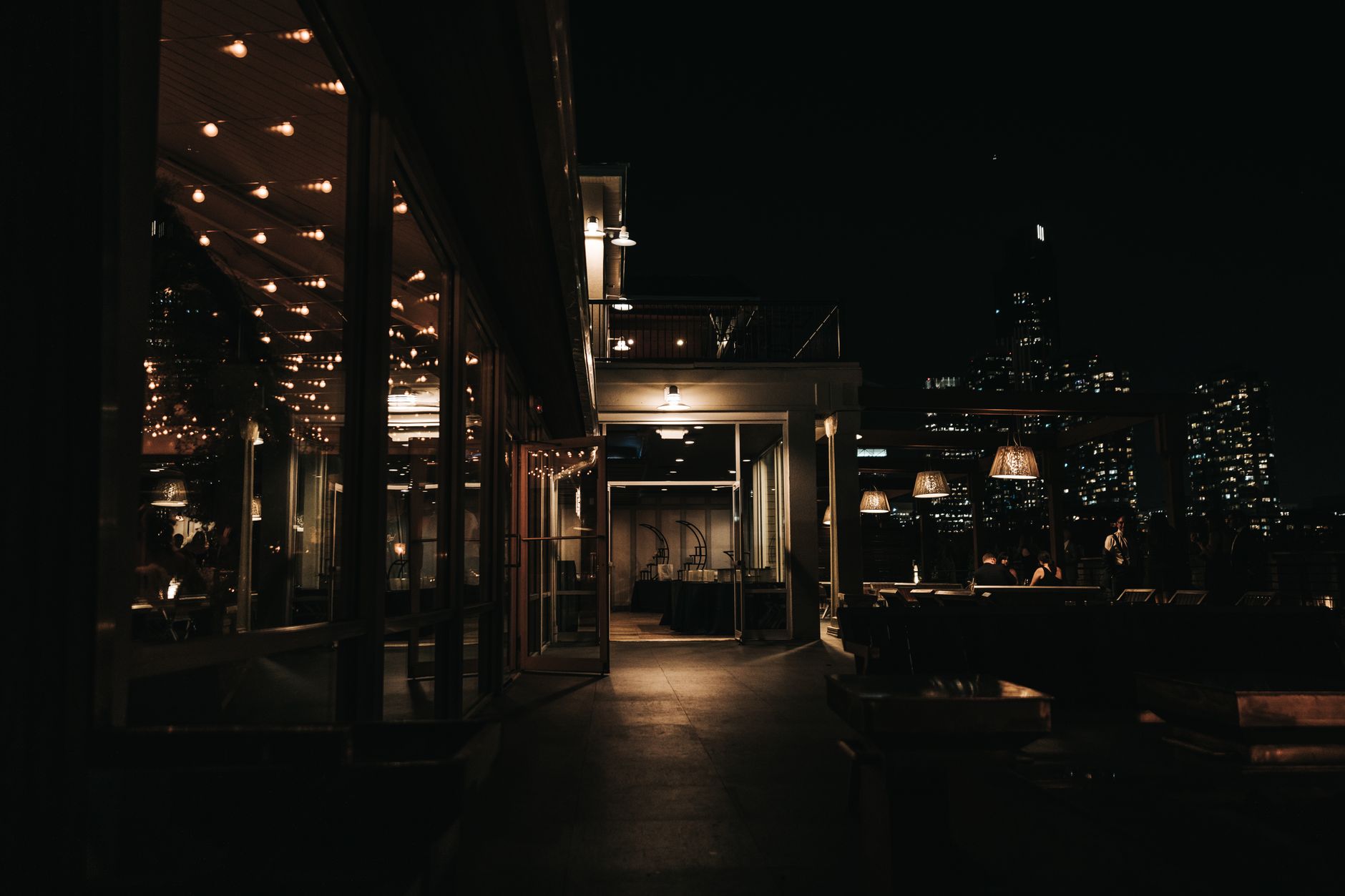 A stylish rooftop bar at night with a city skyline view