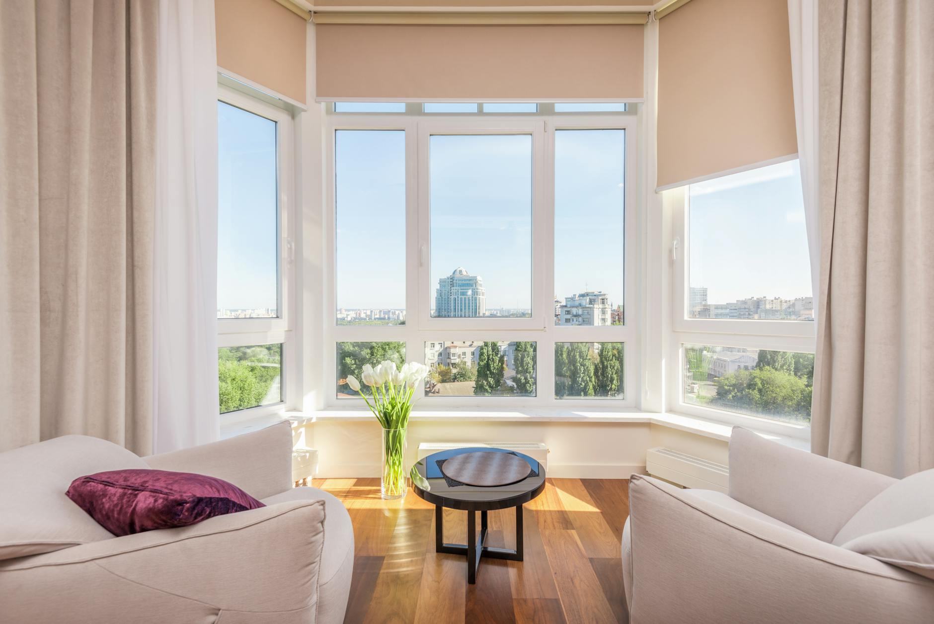 A modern apartment interior with armchairs by windows overlooking the city
