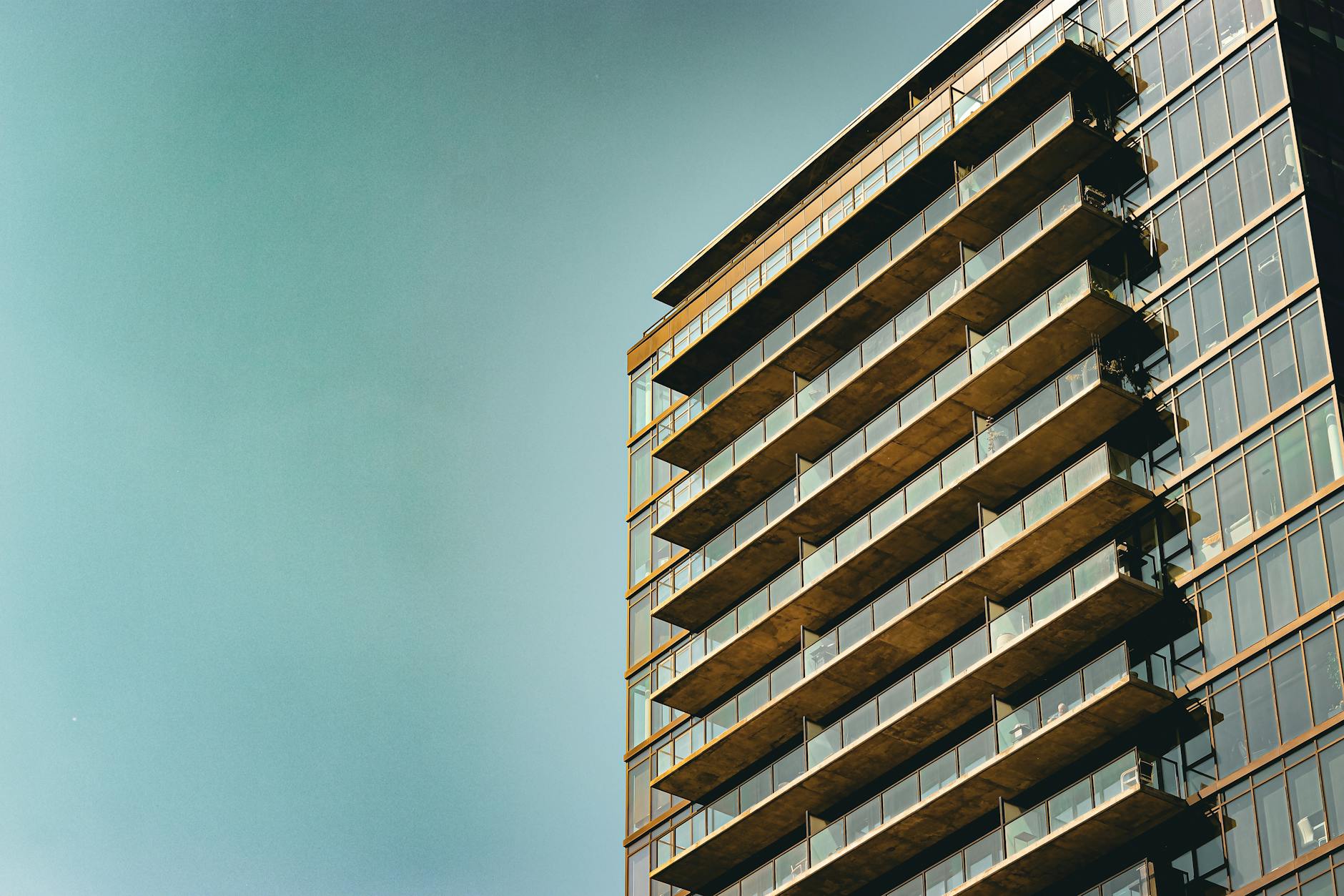 A sleek modern apartment building with a glass facade and balconies