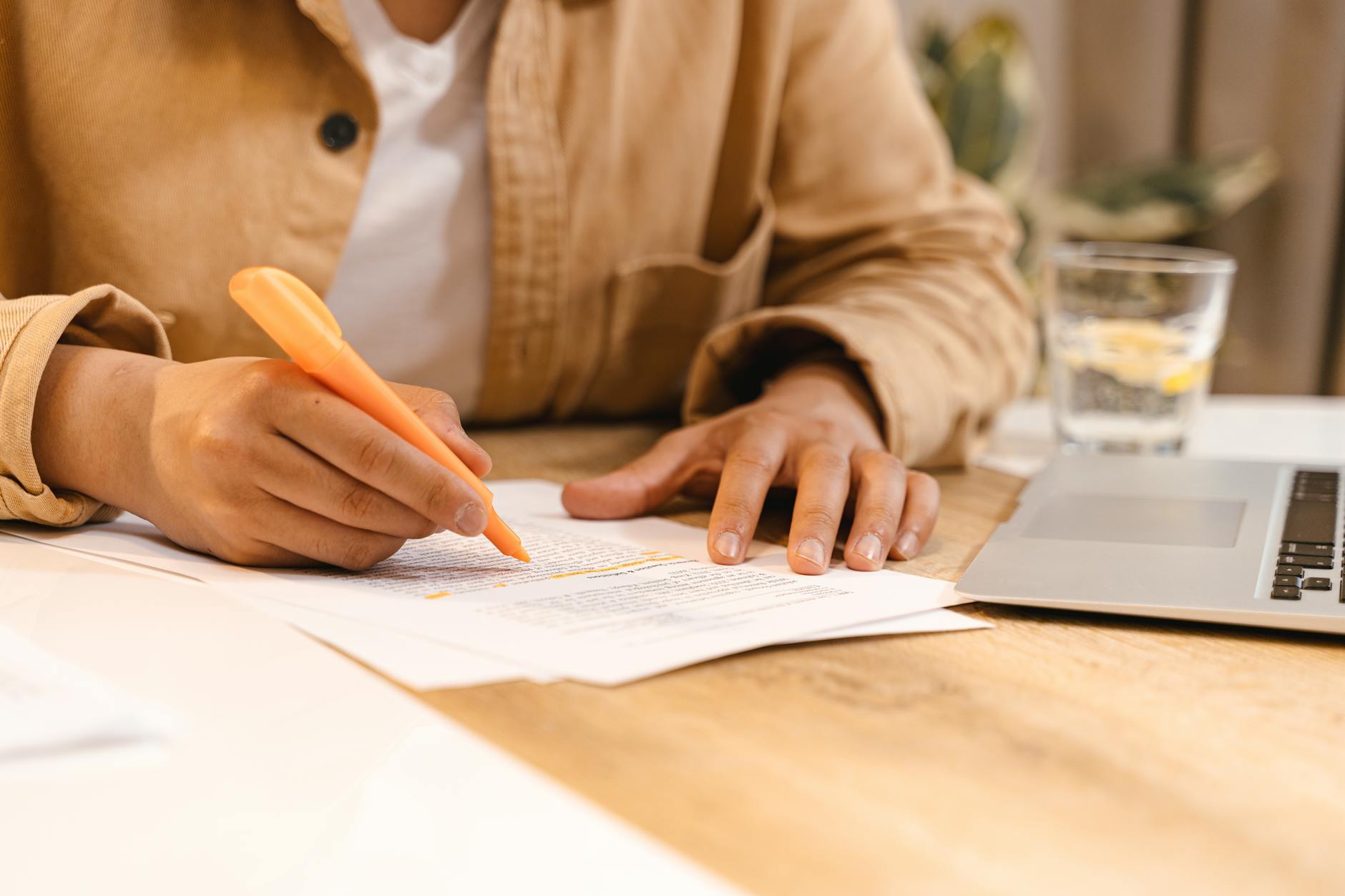 A person reviewing notes at a desk with a laptop