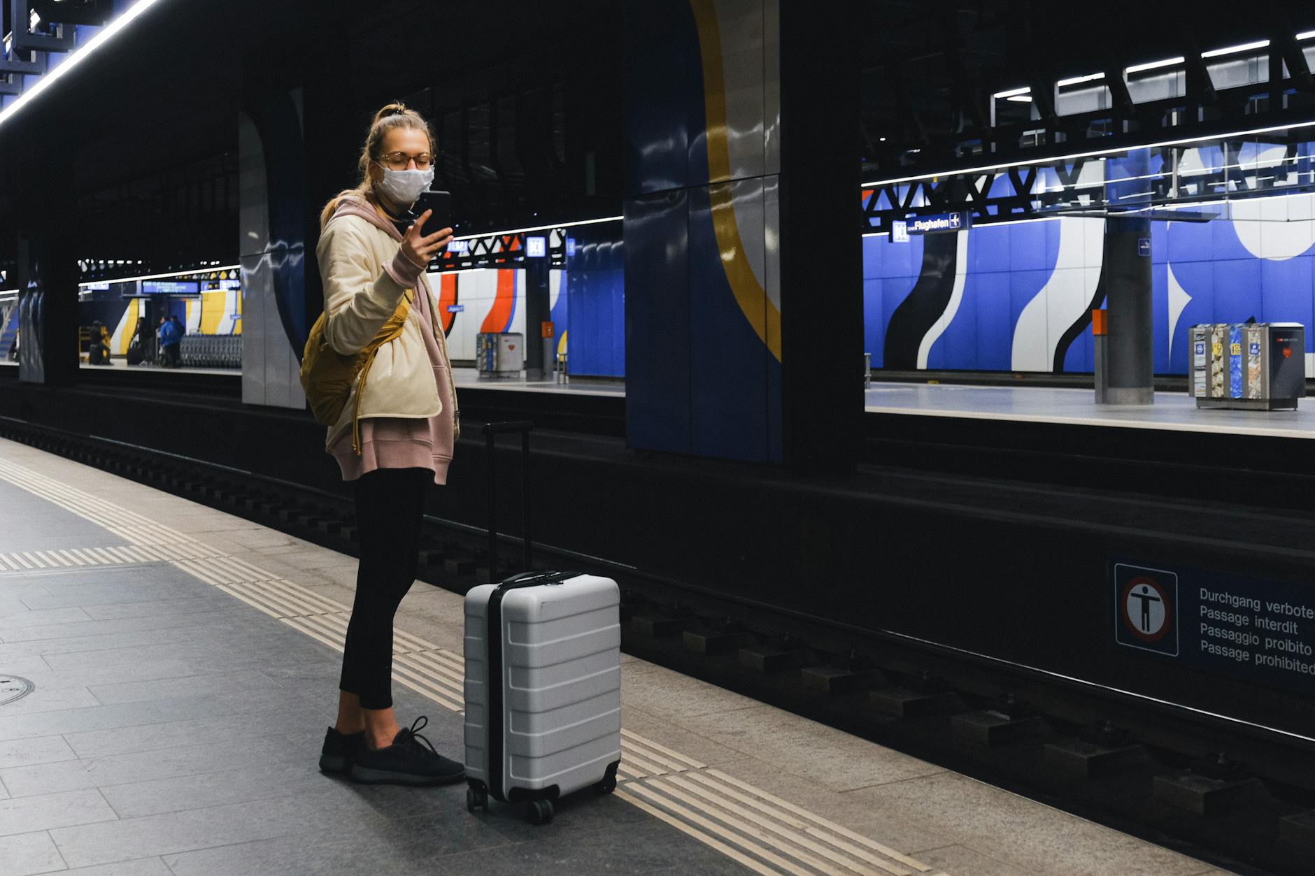 A traveler checking a phone on a train platform