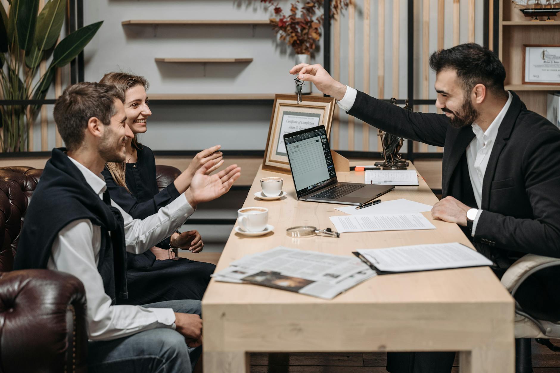 A professional handing apartment keys to a smiling couple at a desk