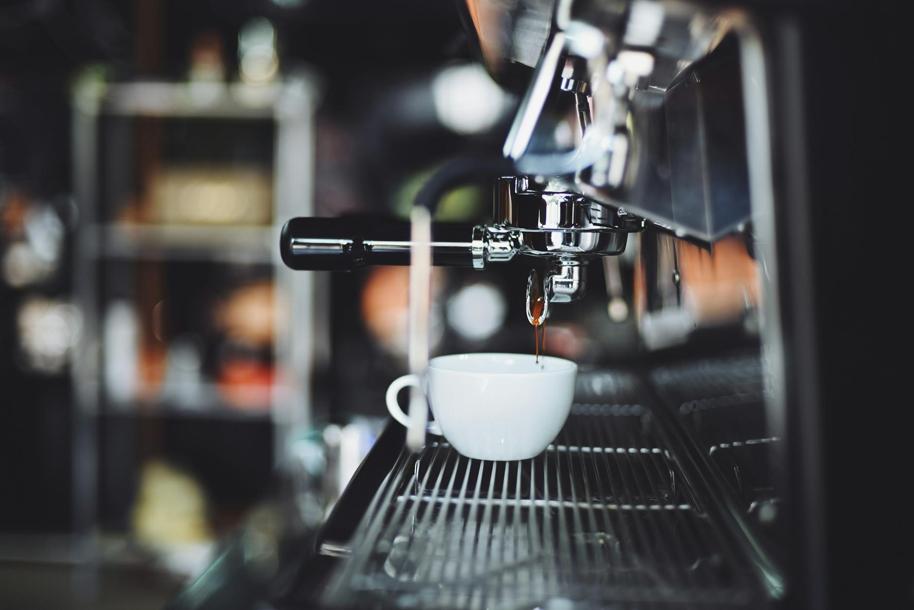 An espresso machine brewing coffee into a cup at a cafe