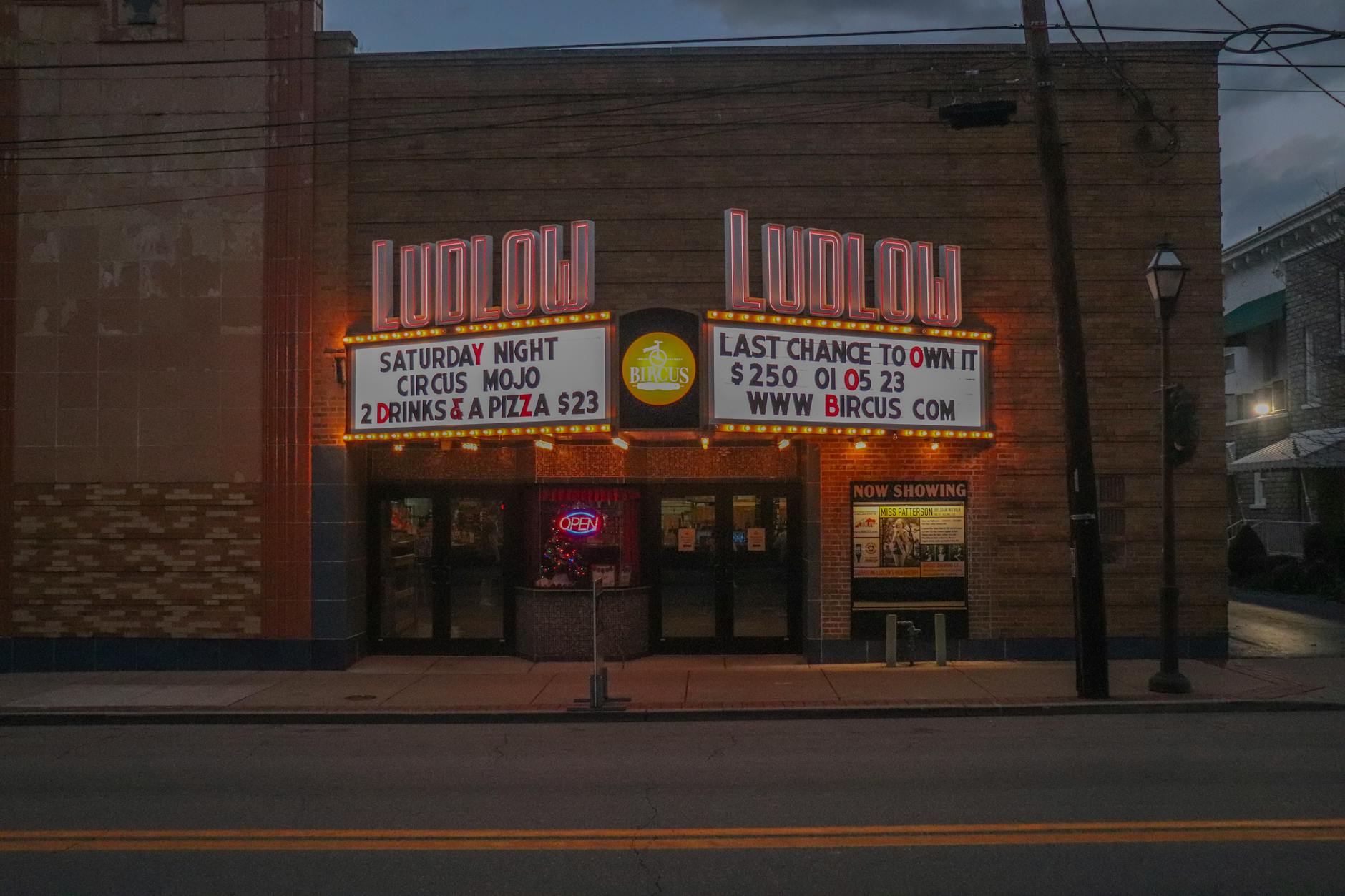 A neon-lit vintage movie theater marquee at dusk