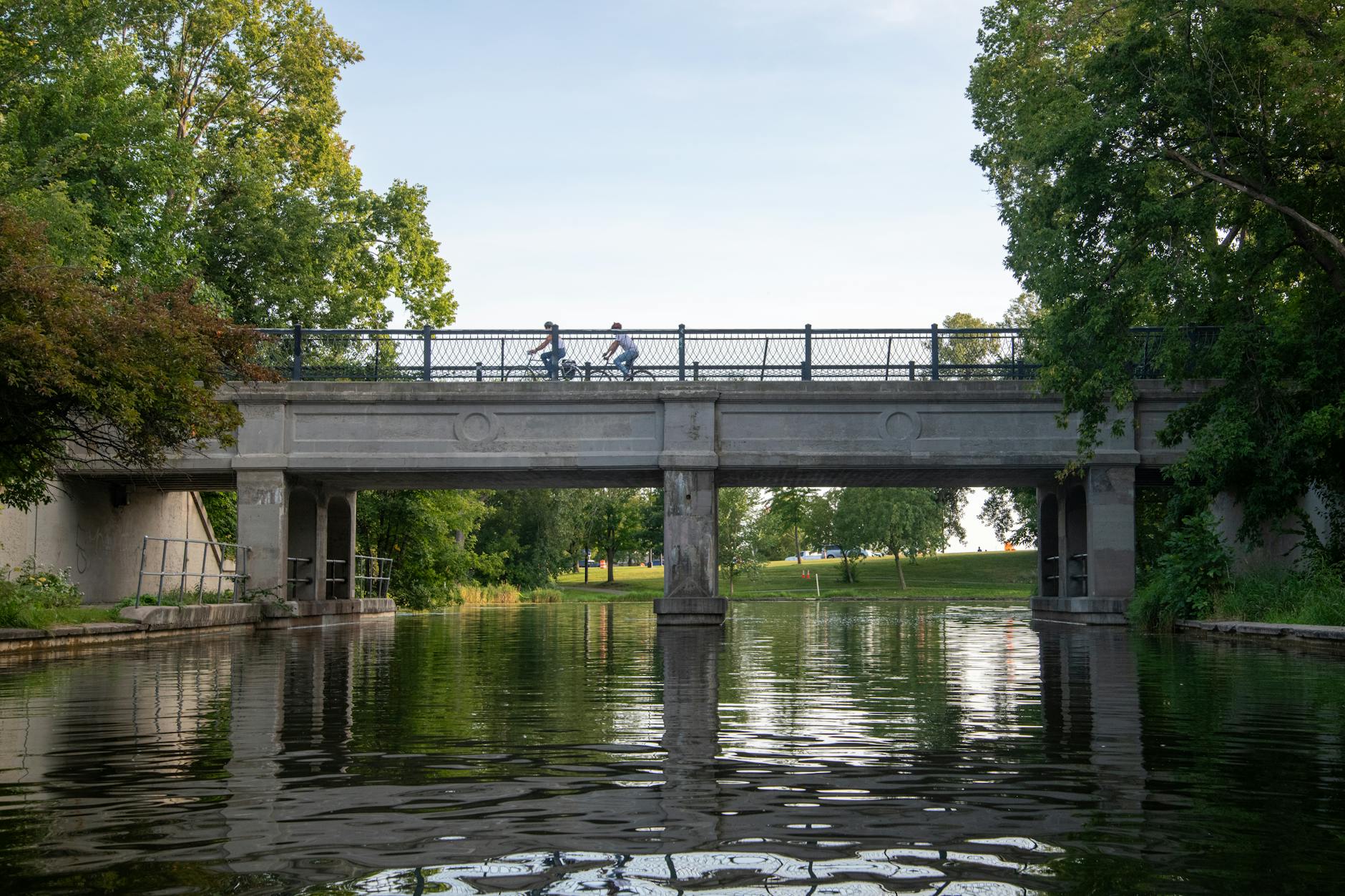 Cyclists riding a trail beside the water surrounded by greenery